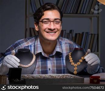 Young male jeweller working at night in his workshop. The young male jeweller working at night in his workshop