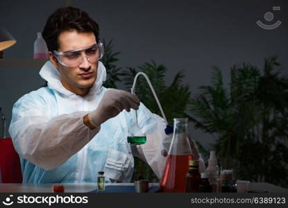 Young male lab chemist late at night in overtime time