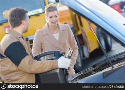 young male mechanic explaining problems to female customer in garage