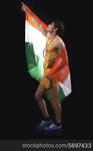 Young male medalist with Indian flag pointing up over black background