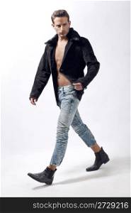Young male model wearing winter jacket and walking over white background