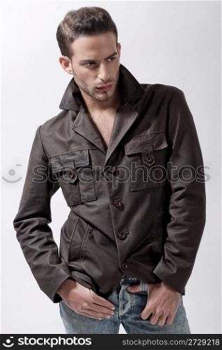 Young male model with brown jacket over grey background