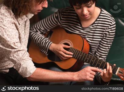 Young Male Musician Teaches Female Student How To Play the Guitar.