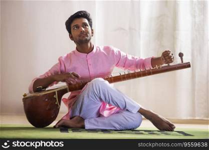 Young male musician tuning his sitar while sitting in living room