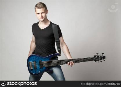 young male musician with six-string bass guitar isolated on light background