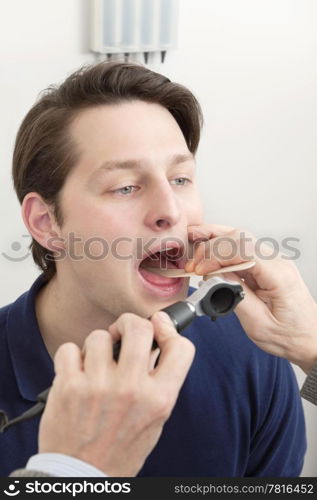 Young male patient getting his tongue and mouth checked for infection by doctor