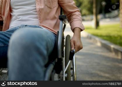 Young male person in wheelchair. Paralyzed people and disability, handicap overcoming. Disabled man walking in park at sunny day. Young male person in wheelchair, paralyzed people
