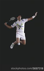 Young male player holding badminton racket while jumping in mid-air