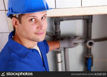 Young male plumber installing pipes