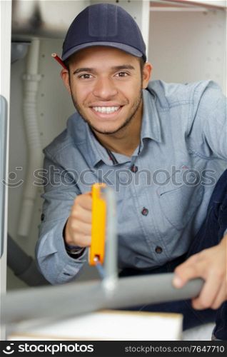 young male plumber sawing through pvc pipe