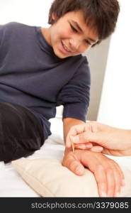 Young male receiving shonishin acupuncture on his hand with a Yoneyama tool. Shallow depth of field, focus on tool.