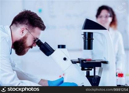 Young Male Researcher Looking At S&les Under Microscope
