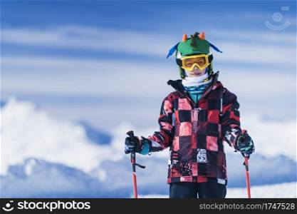 Young male skier in colorful outfit on top of mountain ski resort. Copy space for text.. Skiing Boy on a Mountain Top