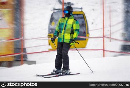 Young male skier riding down the slope at snowstorm