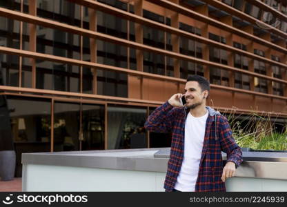 Young male smiling and talking on mobile phone outside