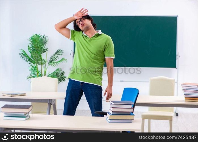 Young male student in front of green board 