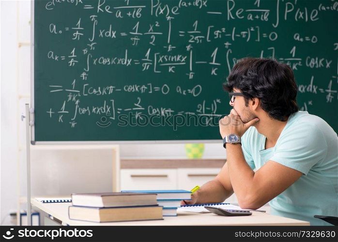 Young male student mathematician in front of chalkboard 