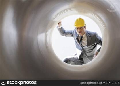 Young male supervisor examining large pipe at construction site