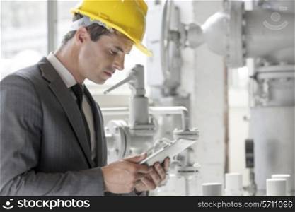 Young male supervisor using tablet PC in industry