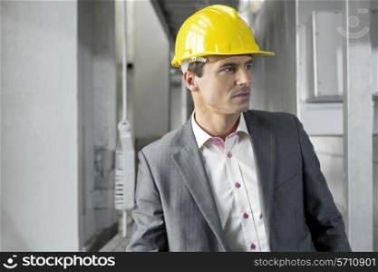 Young male supervisor wearing hard hat looking away in industry