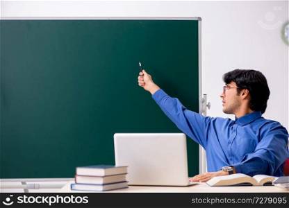 Young male teacher in front of chalkboard  