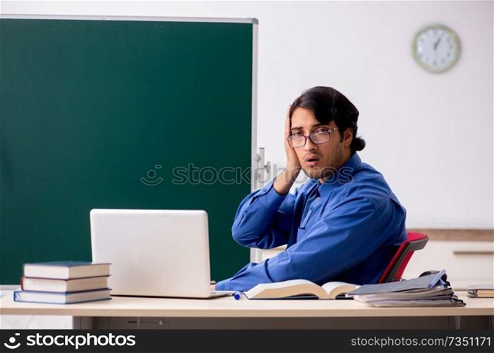 Young male teacher in front of chalkboard  