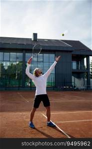 Young male tennis player engaged in training on outdoor sports court. Man in sportswear hitting ball with racket. Young male tennis player engaged in training on outdoor sports court