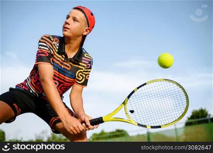 Young male tennis player with racket hits the ball on outdoor court, hitting in action. Active healthy lifestyle, sport game competition, fitness training with racquet. Young male tennis player with racket hits the ball