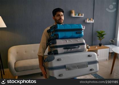 Young male tourist hurrying for vacation trip. Guy carrying suitcase heap. Travel light concept. Young male tourist hurrying for vacation trip