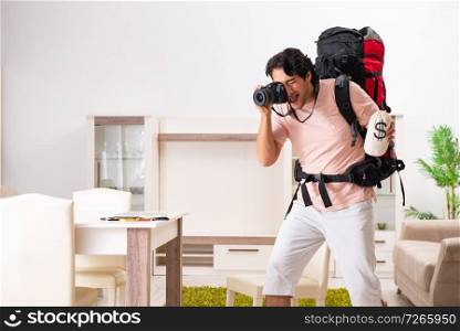 Young male tourist preparing for trip at home 