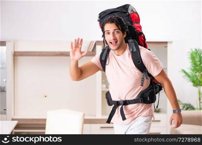 Young male tourist preparing for trip at home 