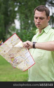 Young male tourist with map in hand looking at wristwatch. Tourist map of the city of Moscow, Russia (no trademark)