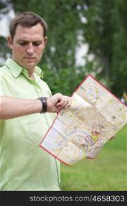 Young male tourist with map in hand looking at wristwatch. Tourist map of the city of Moscow, Russia (no trademark)