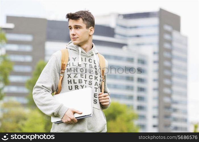 Young male university student holding books at campus