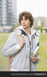 Young male university student holding textbooks at campus