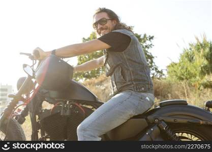 Young male wearing sunglasses on a chopper motorcycle
