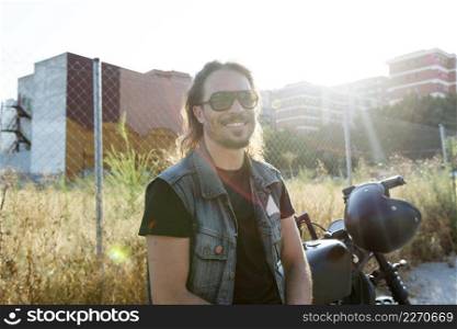 Young male wearing sunglasses on a chopper motorcycle looking at camera