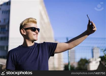 Young male with sunglasses taking a selfie outdoors