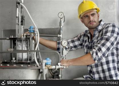 Young male worker examining machine in industry