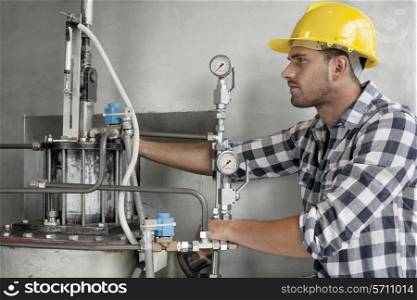 Young male worker examining machine in industry