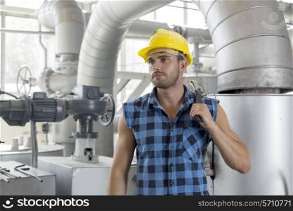 Young male worker holding wrench in industry