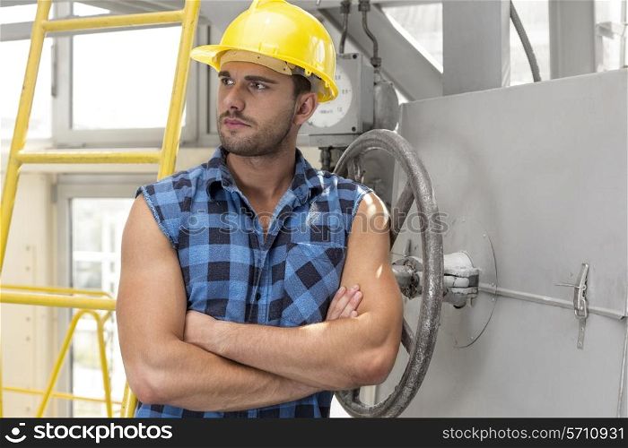 Young male worker standing arms crossed in industry