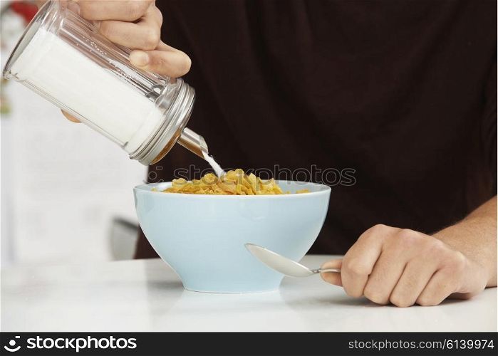 Young Man Adding Sugar To Breakfast Cereal
