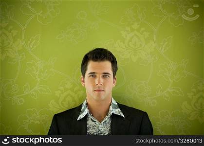 Young man against floral wallpaper.