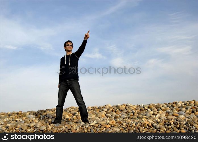 young man alone pointing at the beach