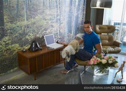 Young man and a dog in front of a laptop