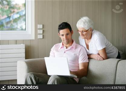Young man and a senior woman looking at a laptop