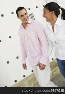 Young man and a teenage girl holding hands and walking