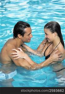Young man and a teenage girl looking at each other in a swimming pool