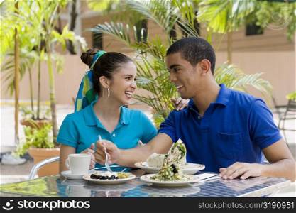 Young man and a teenage girl sitting in a restaurant and smiling